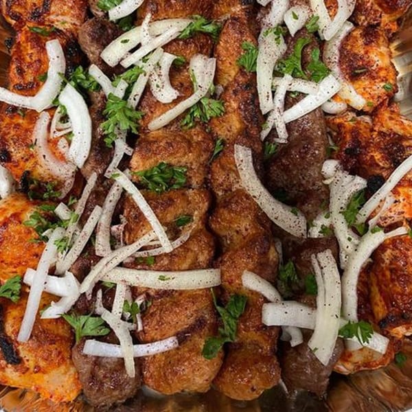 Grilled chicken and beef kebabs from Tonir Cafe, garnished with fresh onions and parsley.