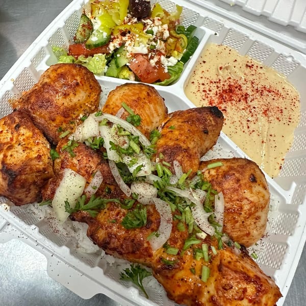 Tonir Cafe's Mediterranean chicken and rice platter with salad and hummus in a takeout container.
